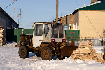 An old small tractor and a pile of chopped firewood at a house in the village