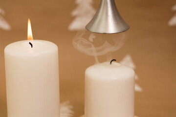 Christmas composition – white candles with mistletoe berries, with female hand holding candle snuffer.