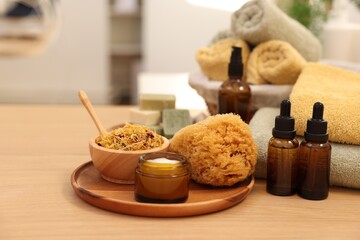 Dry flowers, bottles of essential oils, loofah and jar with cream on wooden table indoors. Spa time
