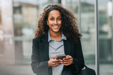 Portrait of smiling female business professional holding smart phone