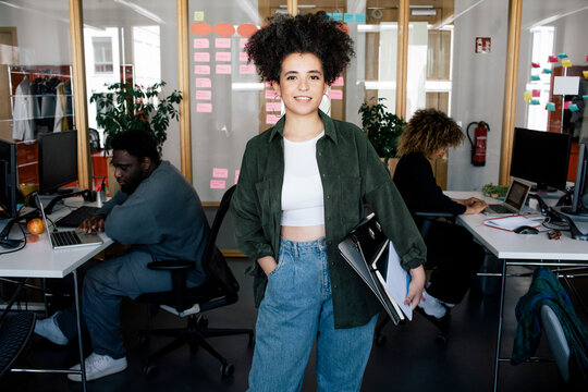 Portrait of confident female computer programmer standing with hand in pocket at office