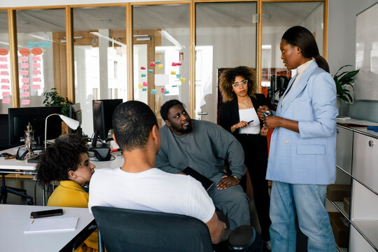 Businesswoman conducting meeting with male and female colleagues at office