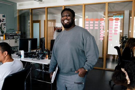 Portrait of happy male entrepreneur standing with hand in pocket at office