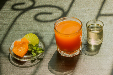 A glass with cold carrot juice on a black table in front of the window.