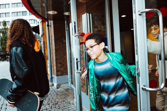 Multiracial Male And Female Friends Coming Out From Building Entrance