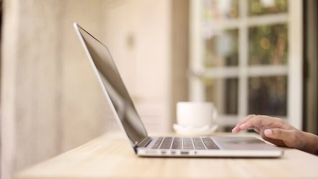 A woman's hand closes a laptop and slowly closes it. Turn off the laptop screen when work is complete.

