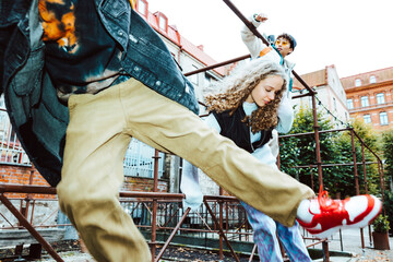 Multiracial male and female friends jumping over railing against building