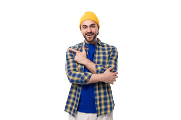 young stylish brunette man with a beard and mustache in a shirt and hat thinks holding his head