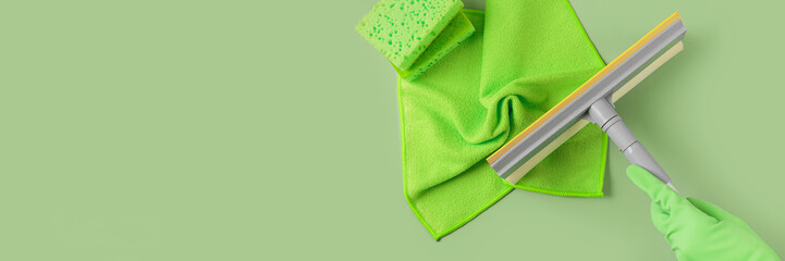 Set for cleaning windows and other surfaces on green background. Hand in rubber glove with mop....