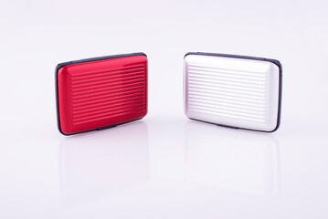 Red and white plastic credit card case on white reflective background.
