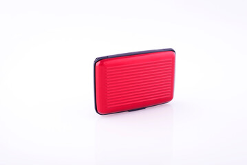 Red plastic credit card case on white reflective background.
