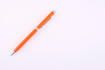 Orange ballpoint pen on a reflective white background.
