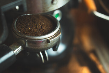 Close up ground arabica coffee from an electric grinder inside portafilter ready for brewing good...