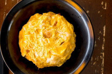 Creamy omelet on rice in black bowl. Soft omelet cover rice