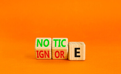 Notice or ignore symbol. Concept word Notice or Ignore on wooden cubes. Beautiful orange table...