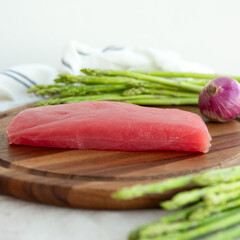 raw tuna fillet and fresh asparagus on a wooden cutting board