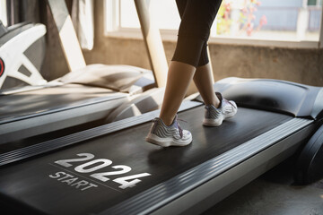Happy new year 2024,2024 symbolizes the start of the new year. Close up of feet, sportswoman runner running on treadmill in fitness club. Cardio workout. Healthy lifestyle, guy training in gym. - obrazy, fototapety, plakaty