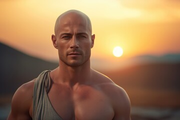 A man wearing a tank top stands in front of a beautiful sunset. Perfect for travel, nature, and outdoor-themed designs