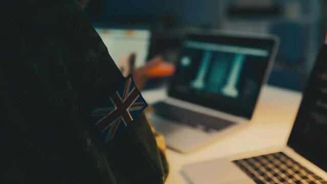 British intelligence officer working laptop in office, gathering intel on enemy