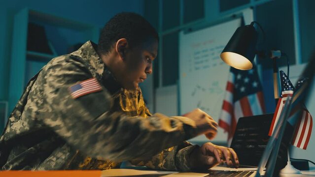 African American U.S. army officer works on laptop, controls military operation