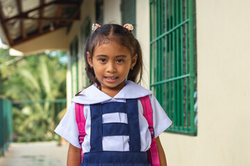 A cute young Filipino girl in a white a blue school uniform, at a provincial primary school. - obrazy, fototapety, plakaty