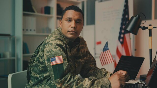 Portrait of serious U.S. army officer working on laptop in office, profession