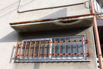 古い集合住宅の窓に取り付けた錆びた鉄柵