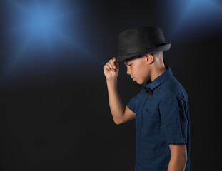 Stylish young man studio stage lights blue background hand to fedora hat brim  - 697280030
