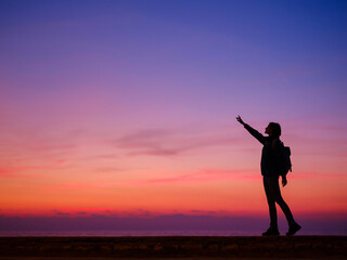 Fototapeta na wymiar Woman tourist against colorful sunset sky. Travel, tourism concept. Active lifestyle.