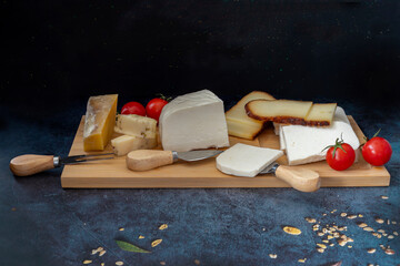 Black background. Various cheeses on wood.