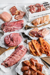 Set of various raw and marinated meat. Meat of beef, veal, chicken, pork, steak, tenderloin, ribs, chicken wings, kebab on craft paper over white background. Meat food, butcher shop, top view