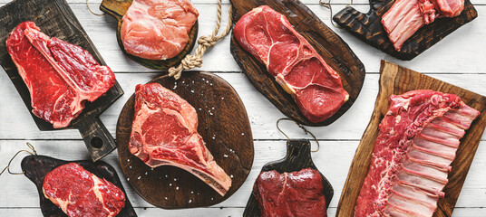 Set of various raw meat steaks. Fresh meat of beef, pork, veal, chicken, steak t-bone, rib eye, tomahawk, ribs, tenderloin on cutting board over white background. Meat food, butcher shop, top view - obrazy, fototapety, plakaty