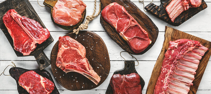 Set of various raw meat steaks. Fresh meat of beef, pork, veal, chicken, steak t-bone, rib eye, tomahawk, ribs, tenderloin on cutting board over white background. Meat food, butcher shop, top view