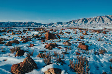Beautiful mountains valley with stones in the snow in winter - obrazy, fototapety, plakaty