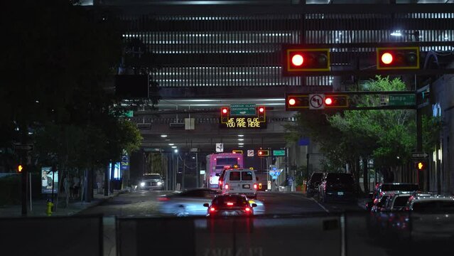 Road intersection in American city with traffic lights and moving cars at night. Transportation system in USA