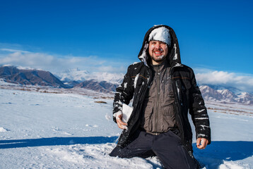 Fototapeta na wymiar Winter portrait of man with snow on his face on mountains background