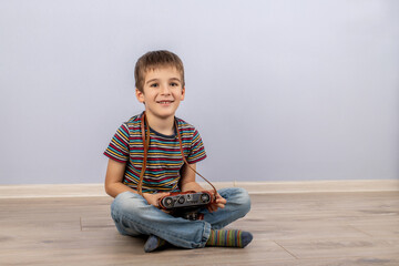 boy in a striped T-shirt sitting on the floor smiling with a retro camera in his hands on a blue background