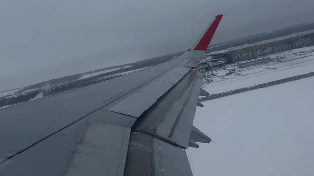 An airplane wing overlooking a snowy airport landscape, possibly depicting the concept of winter travel or aviation during colder months