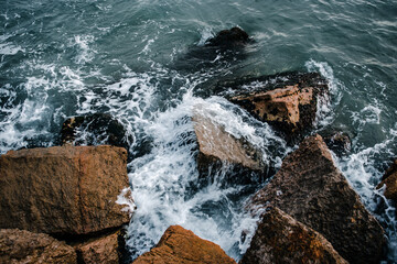 Water with stones on the beach concept photo. Mediterranean winter stormy seaside. Underwater rock with algae.