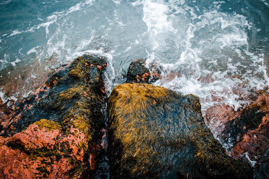 Close up water with stones on the beach concept photo. Mediterranean winter stormy seaside. Underwater rock with algae.
