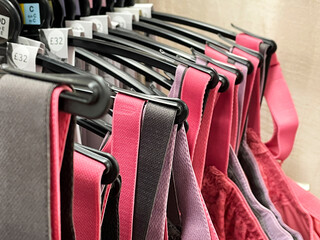 Row of bras hanging in lingerie store, colorful bra straps close up, health
