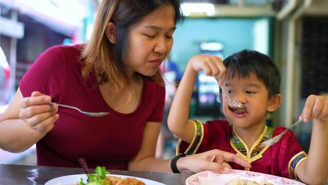 Mom with kindergarten kid boy family eating chicken rice steam travel in Yaowarat China town Bangkok Thailand