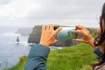 close up of hands with mobile phone taking horizontal photograph of a beautiful seaview with...