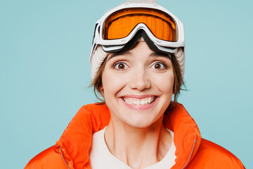 Close up skier excited young woman wear warm padded windbreaker jacket hat ski goggles mask look camera travel rest going to spend weekend winter season in mountains isolated on plain blue background.