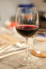 A glass of red wine on the table, with blur background in the restaurant