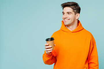 Young man he wears orange hoody casual clothes hold takeaway delivery craft paper brown cup coffee...