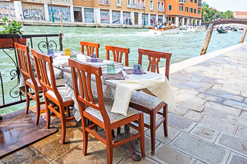 cafe with a table on the street of Venice near the canal on a sunny day