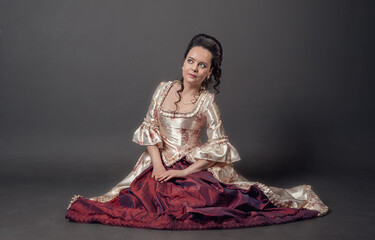 Young beautiful woman in rococo style medieval dress sitting on the floor