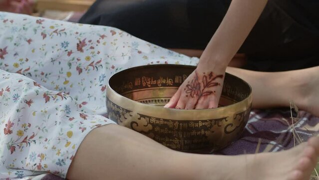 A shaman girl performs a cleansing ritual for prosperity, longevity, fulfillment of desires, rid of failures and illness. Tibetan singing brass bowl and handmade wand near the woman patient feet