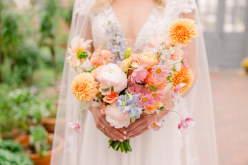 Bride holding a delicate floral arrangement in pastel colors. 